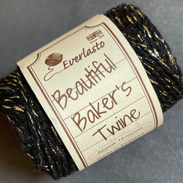 Ball of black and gold baker's twine with a label on a gray background