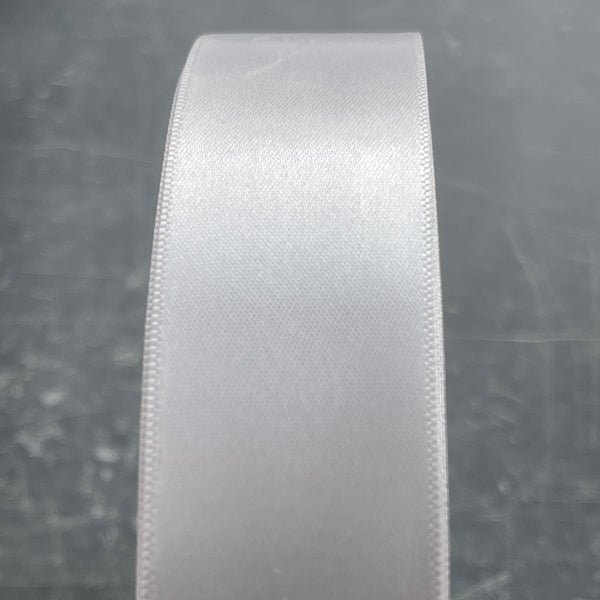 Close-up of a roll of grey satin ribbon on a dark background