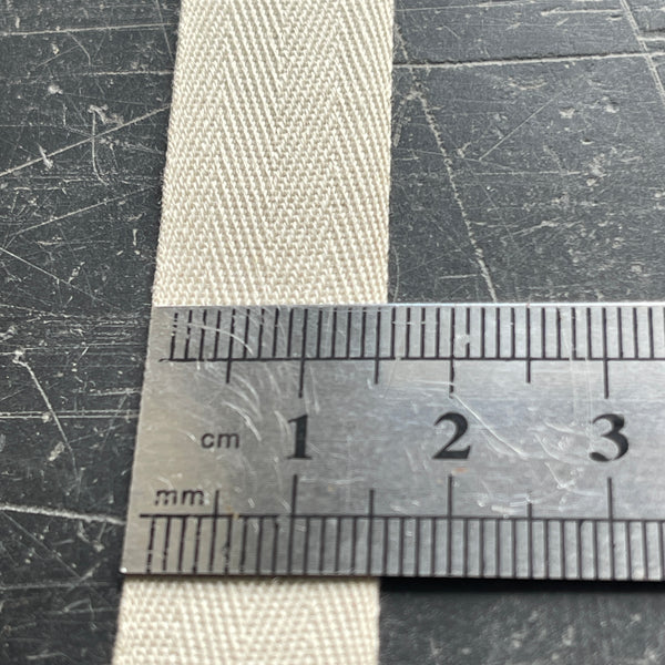 Close-up of a ruler measuring a textured strap on a scratched surface.