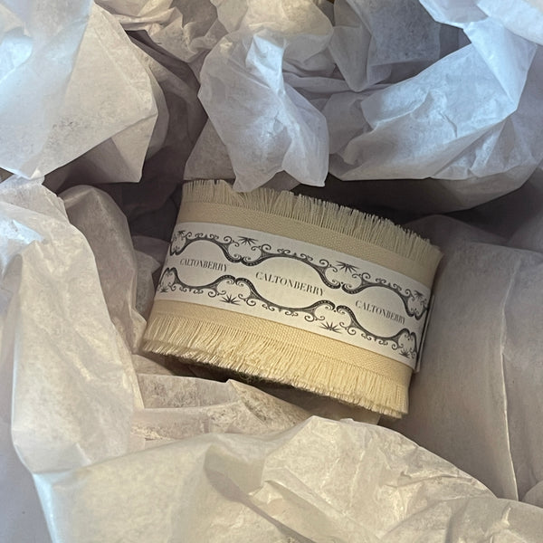 frayed edge cotton ribbon with a decorative label wrapped in white tissue paper