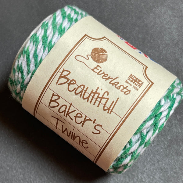 Roll of green and white baker's twine with a label on a gray background
