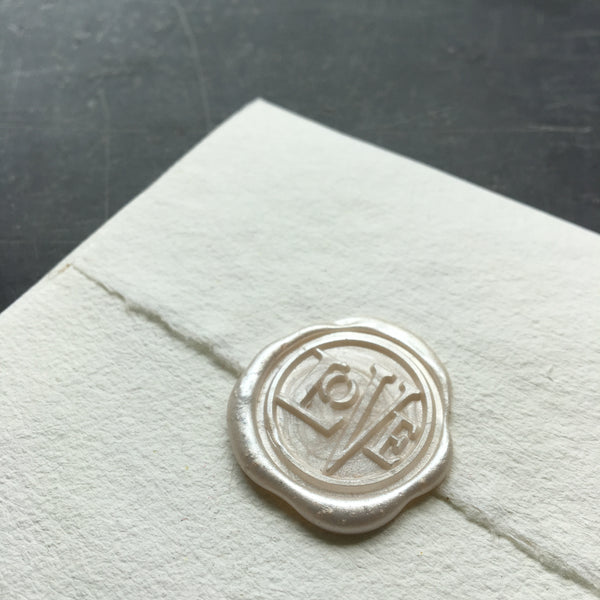 white wax seal on a white envelope against a dark background