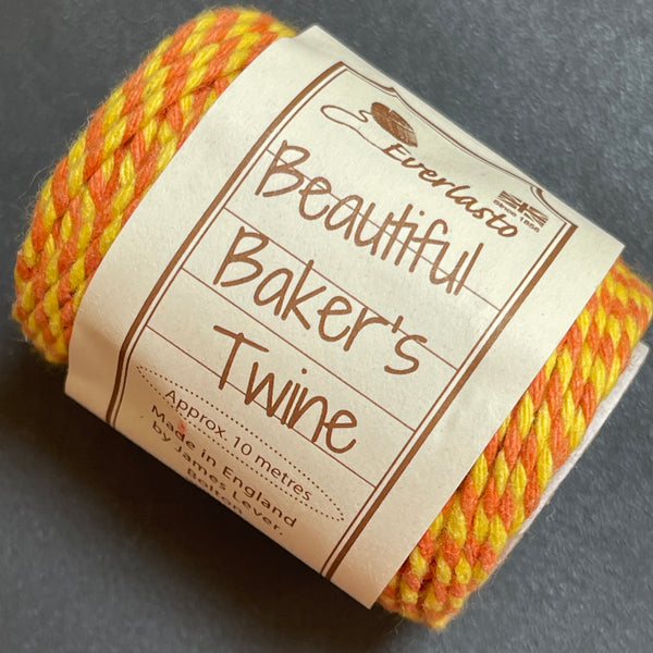 Ball of yellow and orange Baker's Twine with a label on a dark background
